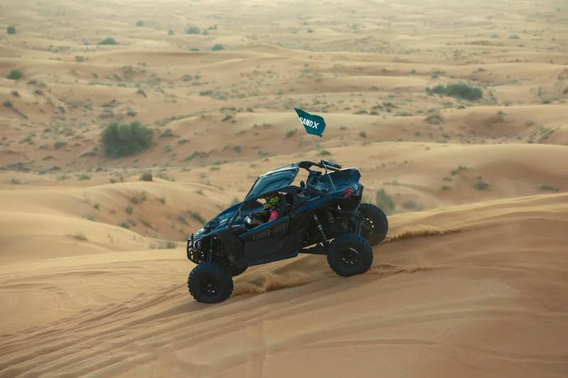 Can-Am Maverick X3 cresting a dune above scrubland