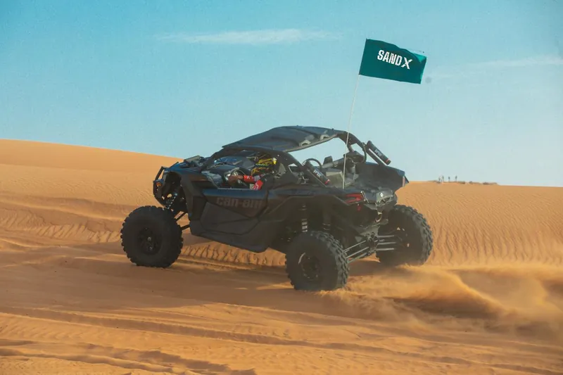 Can-Am Maverick X3 with a SAND X flag against a blue sky