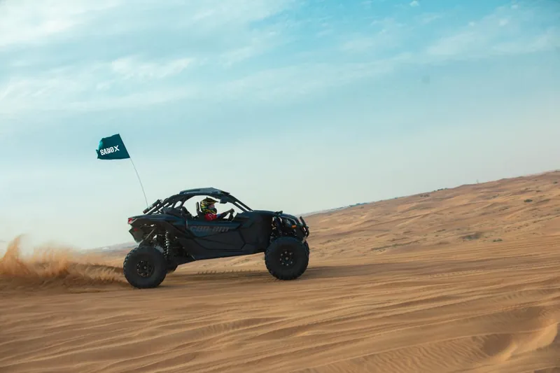 Can-Am Maverick X3 driving past with a sand trail