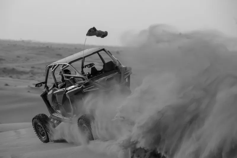 Black and white photo of a buggy in a cloud of sand