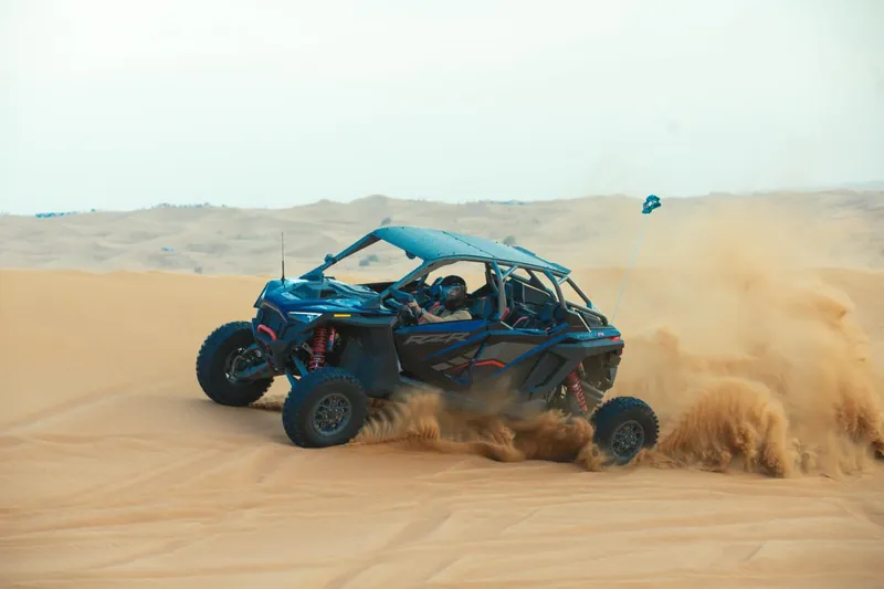 Polaris RZR Pro R four-seat buggy kicking up sand as it turns