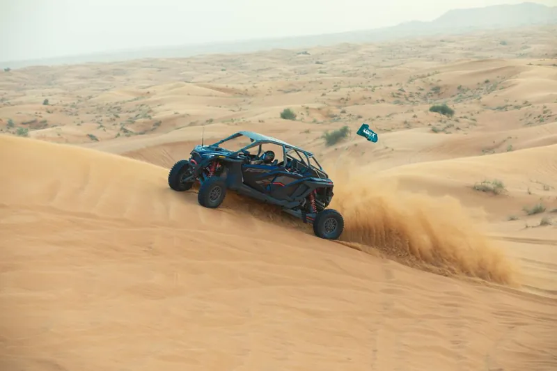 Polaris RZR Pro R four-seat buggy spraying sand on a dune face