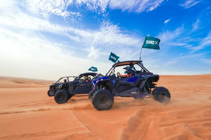 Polaris RZR Turbo S and Can-Am Maverick X3 driving side by side over a dune