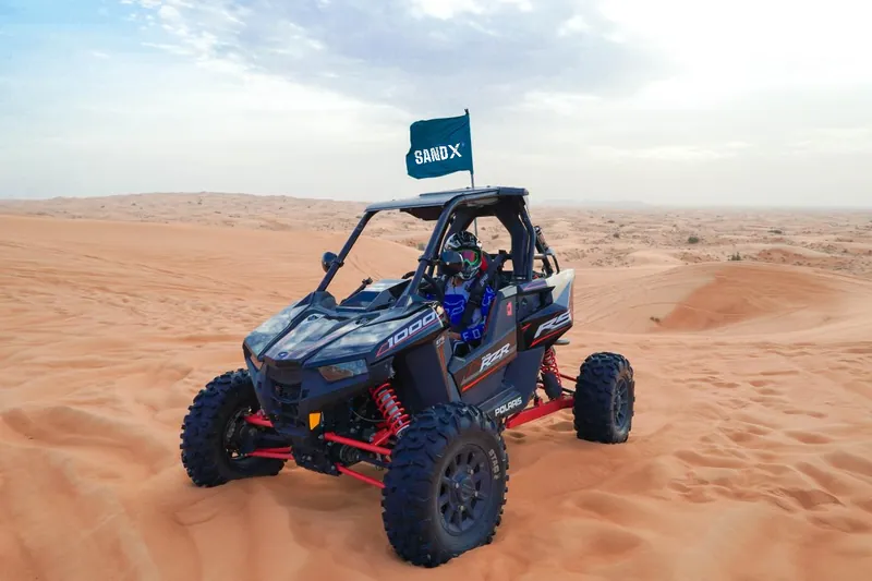 Driver seated in a Polaris RZR RS1 on open dunes
