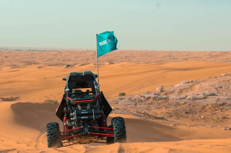 Rear of a Polaris RZR RS1 showing its red suspension arms, with a SAND X flag above