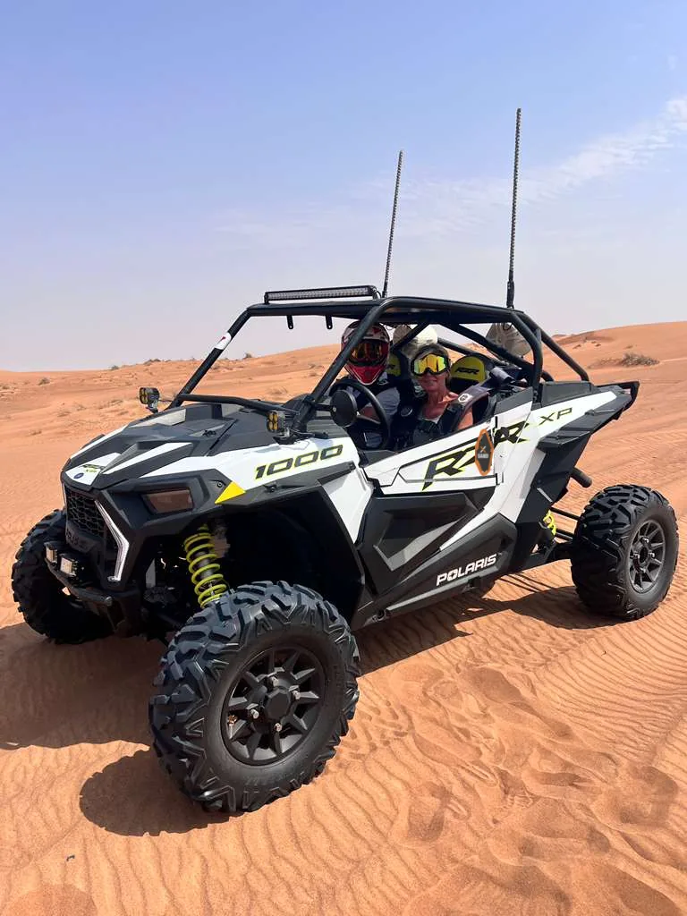 Two riders in a Polaris RZR XP 1000 on the dunes