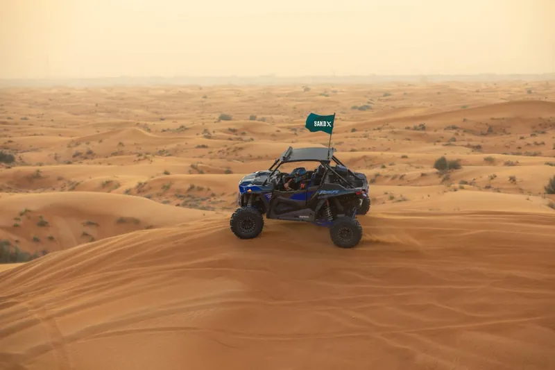 Polaris RZR Turbo S on a dune crest in hazy evening light