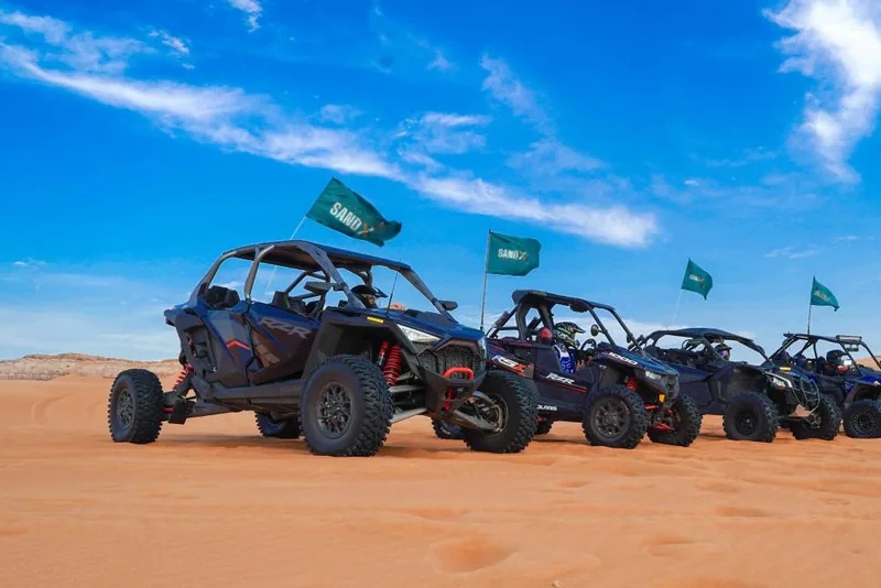 SAND X Polaris and Can-Am buggies lined up on red sand