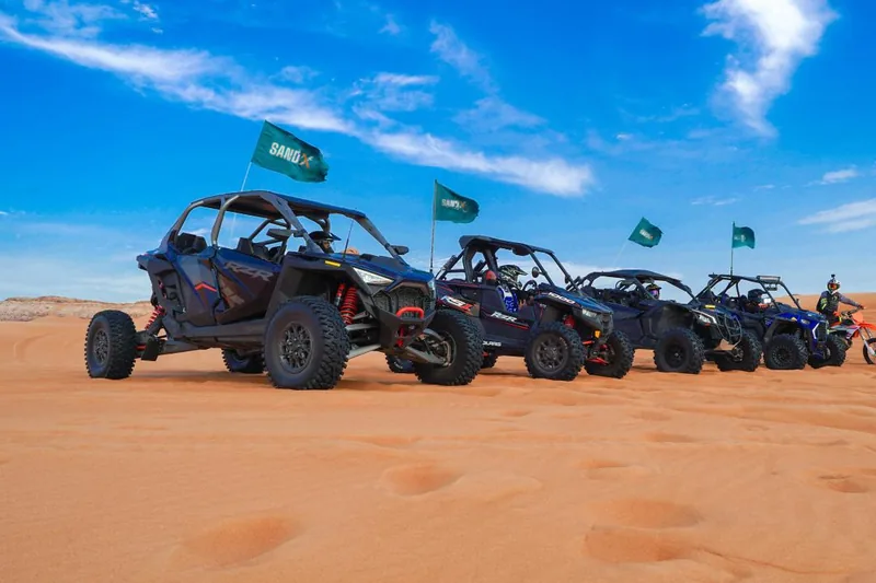 Row of SAND X buggies with flags under a blue sky